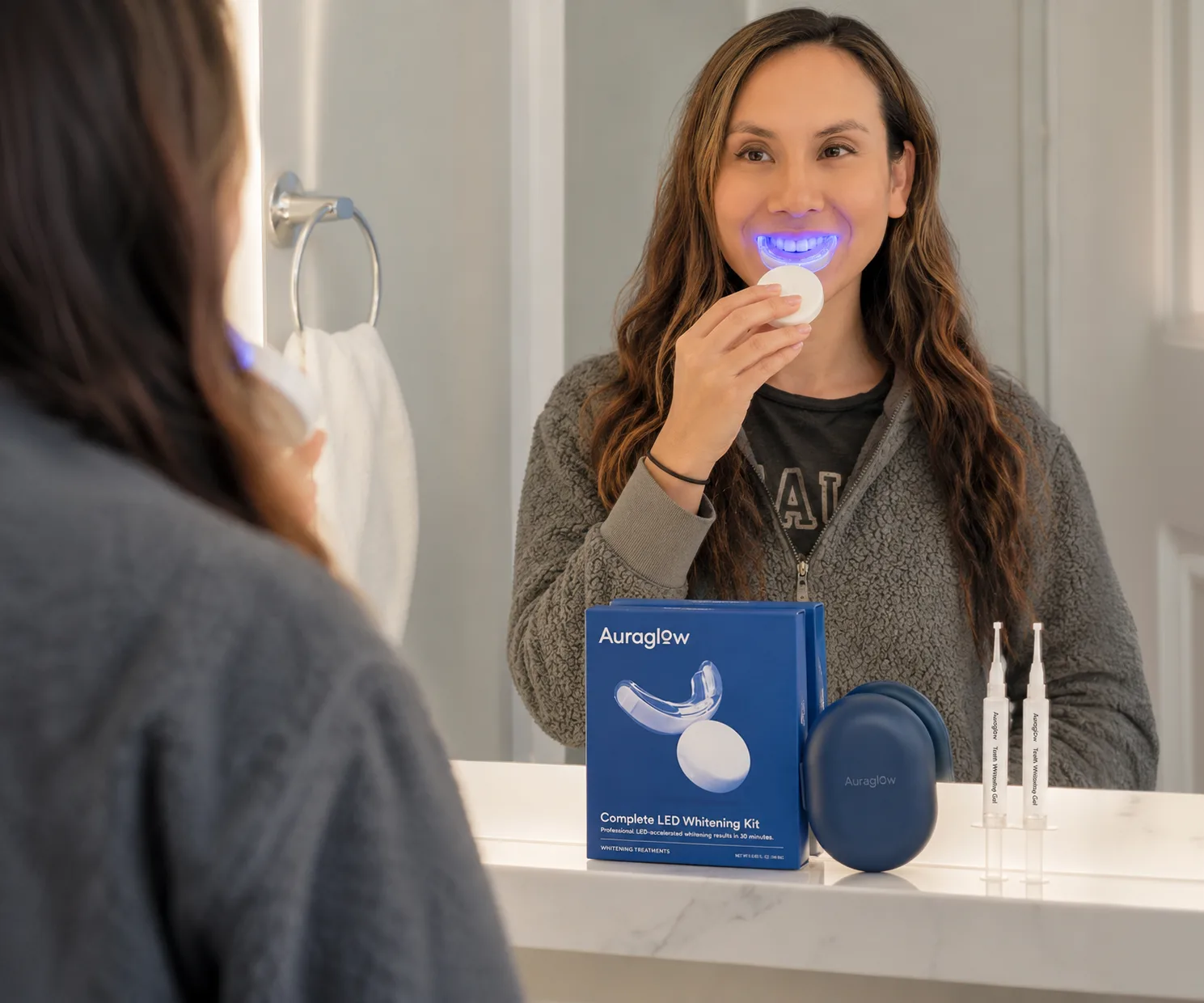 Woman activating Auraglow LED light in bathroom mirror